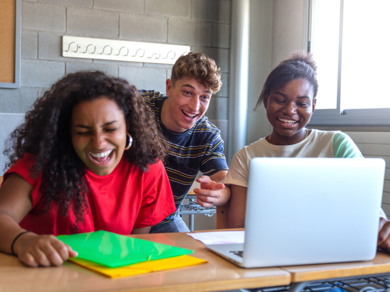 A trio of high schoolers smile and laugh while participating in mental health activities together.