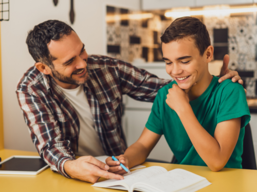 A father in a flannel shirt helping his son in a green shirt set goals for therapy.