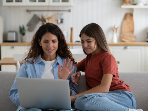 Two people, one with a white shirt and one with a red shirt, sit next to each other looking at a computer where they are attending a DBT group to learn the DBT STOP skill.