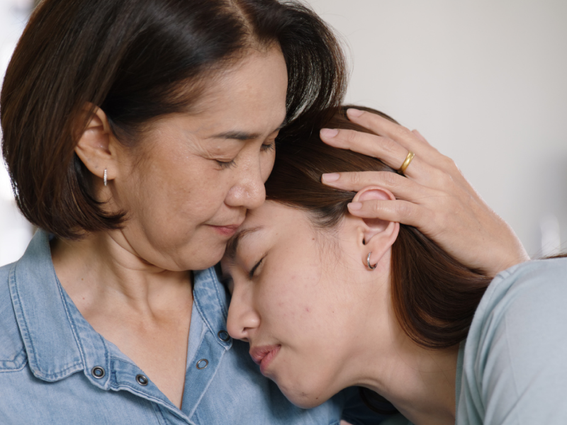 A mother puts her hand on her daughter's head reassuringly. Her daughter has severe OCD but she is able to offer her comfort during treatment.