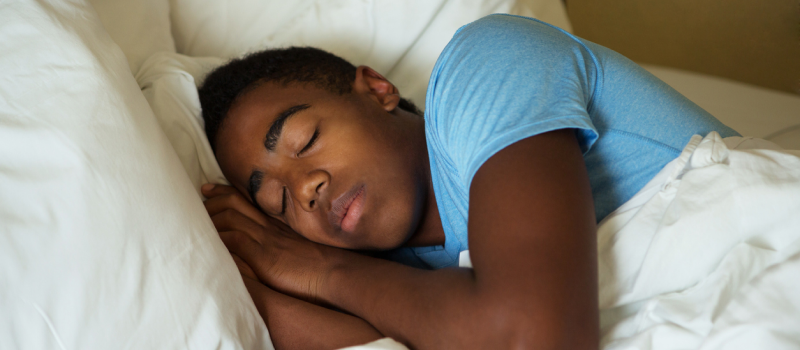 A person in a blue shirt asleep in bed. Despite his nighttime anxiety, he was able to fall asleep after using a guided meditation for sleep and anxiety.