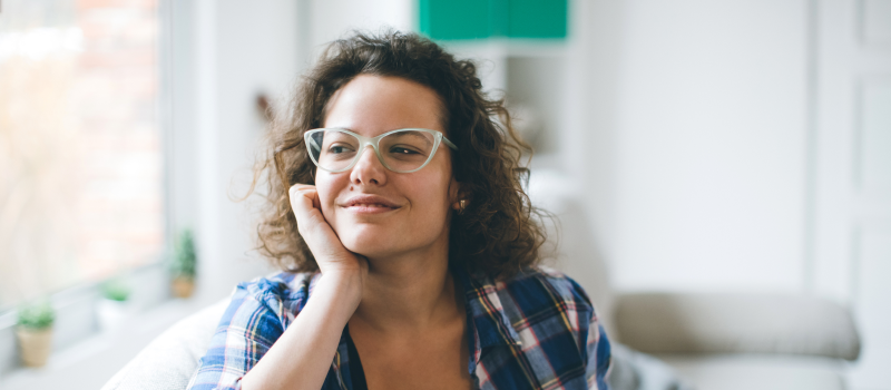 A young woman with teal glasses healing from trauma smiles