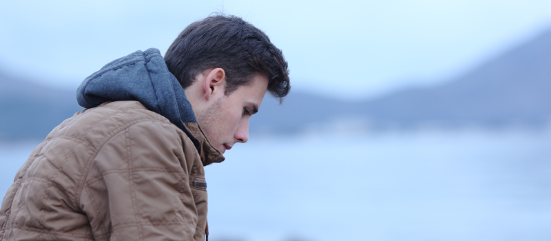 A young male sits on the beach in the winter. He has somatic memories, which is how his mind and body stored trauma.