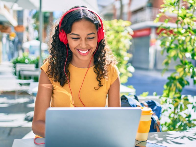 Female teenager sitting at a table on her computer. She is attending virtual Intensive Outpatient Programming from her computer.