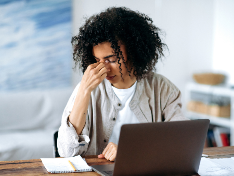 Young male in a white shirt with a grey jacket sitting at a desk with his computer. The teen is suffering from a migraine and is in treatment for depression.