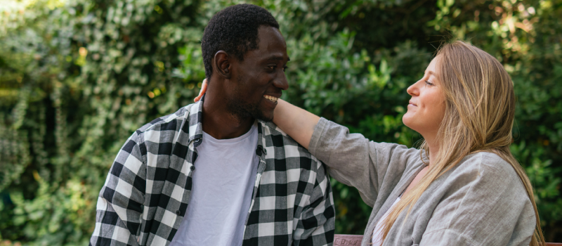 Young couple sitting on a park bench. The female has signs of paranoid personality disorder, and her partner is loving and supporting her.