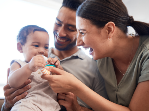 Young parents playing with their infant child. They are navigating how to support their mental health as a new parent.