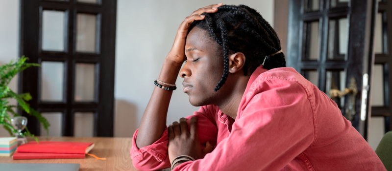 Young male in a red shirt at his desk. The male is struggling with anxiety and receiving support from his partner.