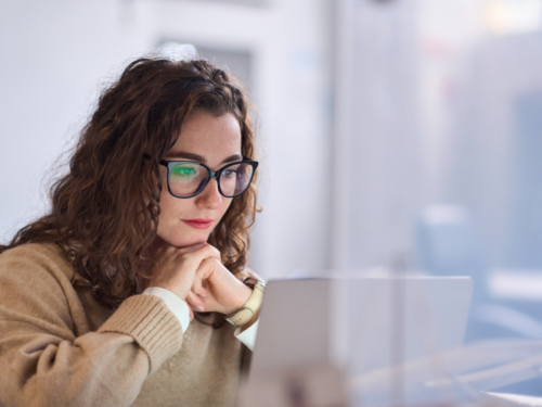 A young woman sits at her desk in a brown sweatshirt. She is a suicide attempt survivor receiving support through Charlie Health's virtual Intensive Outpatient Programming.