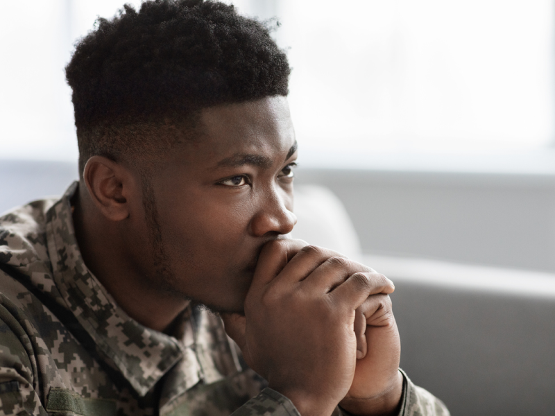 A young male veteran sits on his couch. He is currently in PTSD treatment.