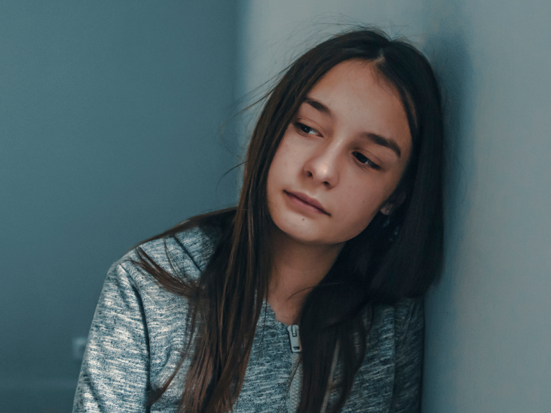 A young female in her room looks sad. She is being treated for quiet borderline personality disorder.