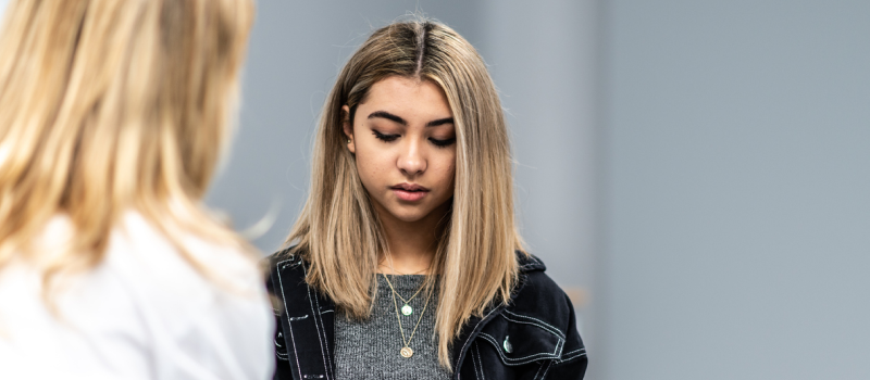 A young female in a black jacket and grey shirt. She is learning about intellectualization.