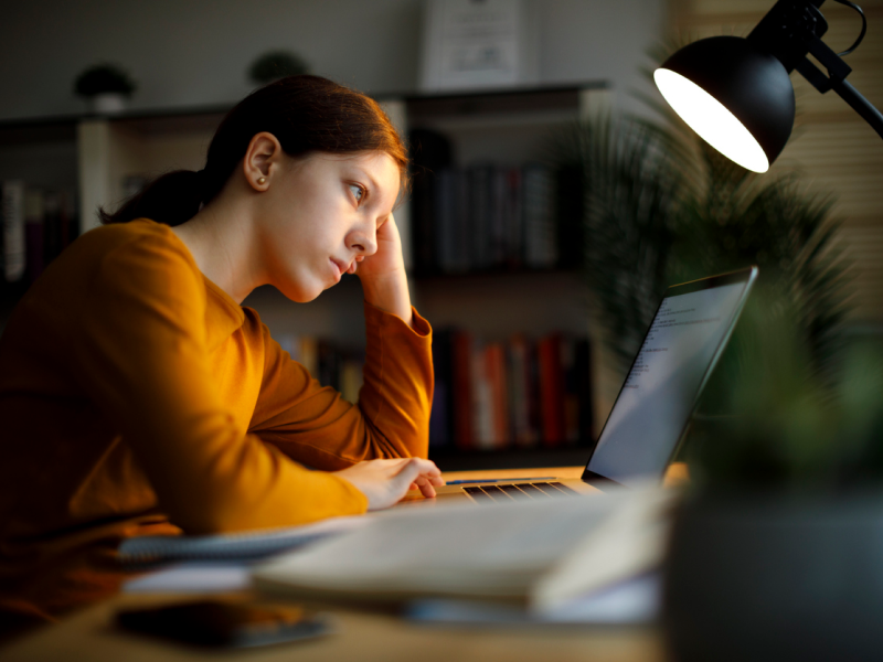 A young woman in an orange shirt sits at her desk. She is experiencing an emotional hangover and is learning what it is and how to cope.