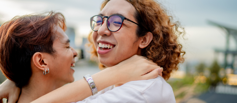 A young couple hugs outside on a walk. They are gender apathetic and prefer not to be labeled as one particular gender.