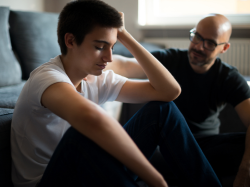 A young male sitting with their father. He has created a self-harm safety plan and is connecting with someone he trusts.