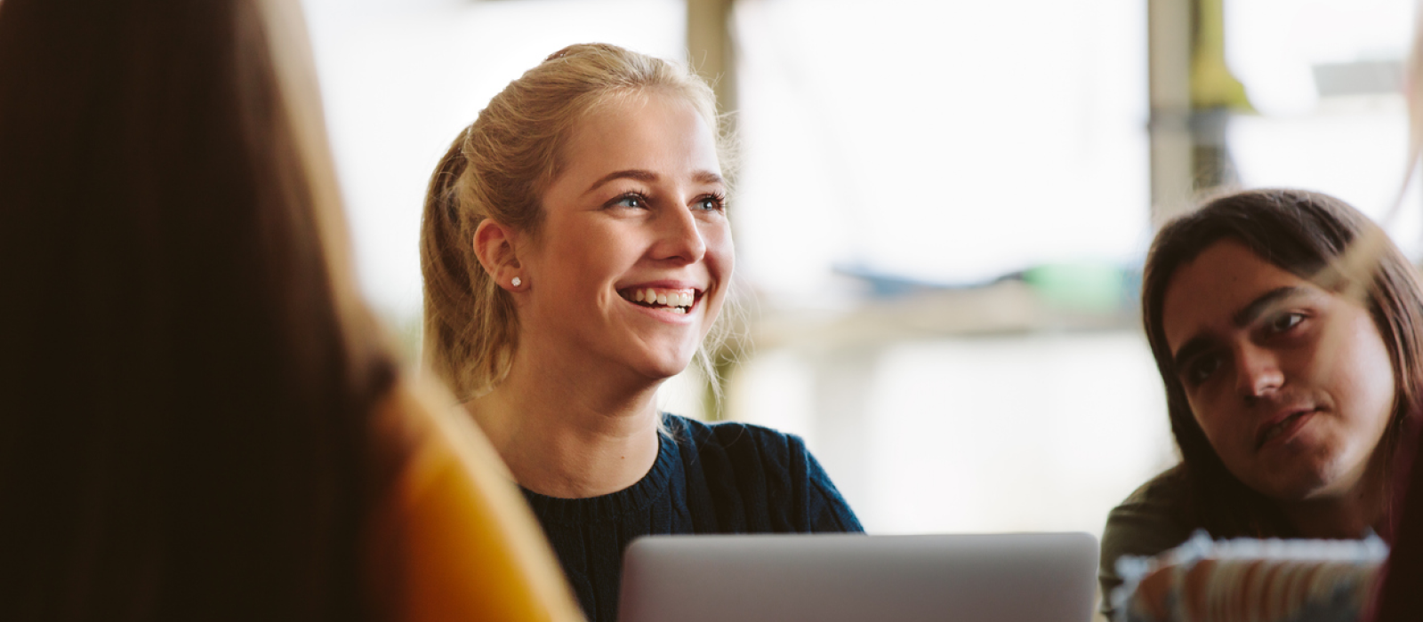 A female teenager sits in her class at school. She is smiling and feels like herself again because of Charlie Health's vIOP.