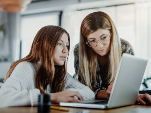 A female teenager and her mother sit at home on their computer. They are reading about the best therapies for OCD according to therapists.