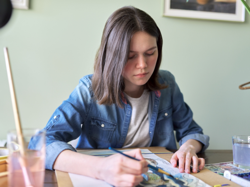 A female teenager is painting at home. She has been