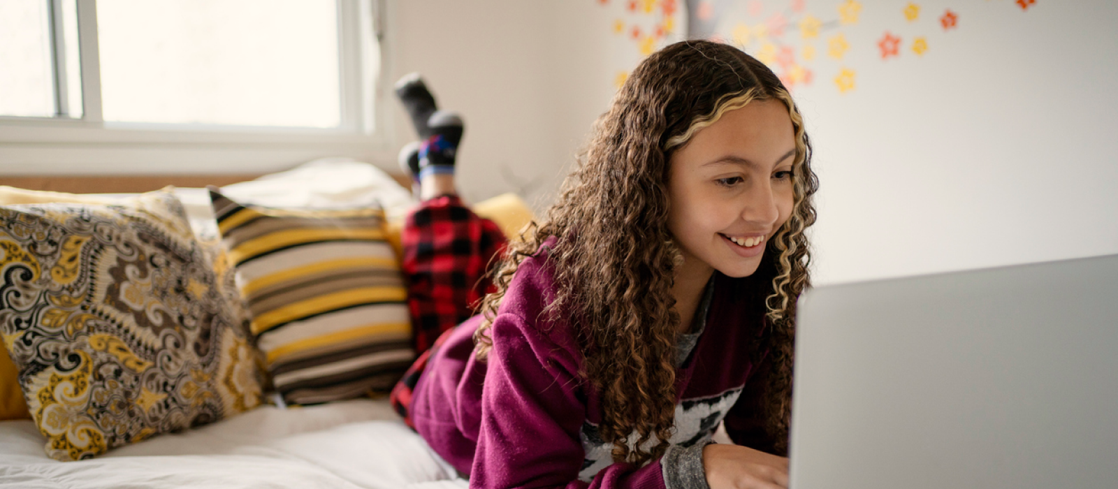 A female teenager lays in her room on her computer. She is in Charlie Health's virtual IOP, which new research has shown reduces mental health-related ED admissions.