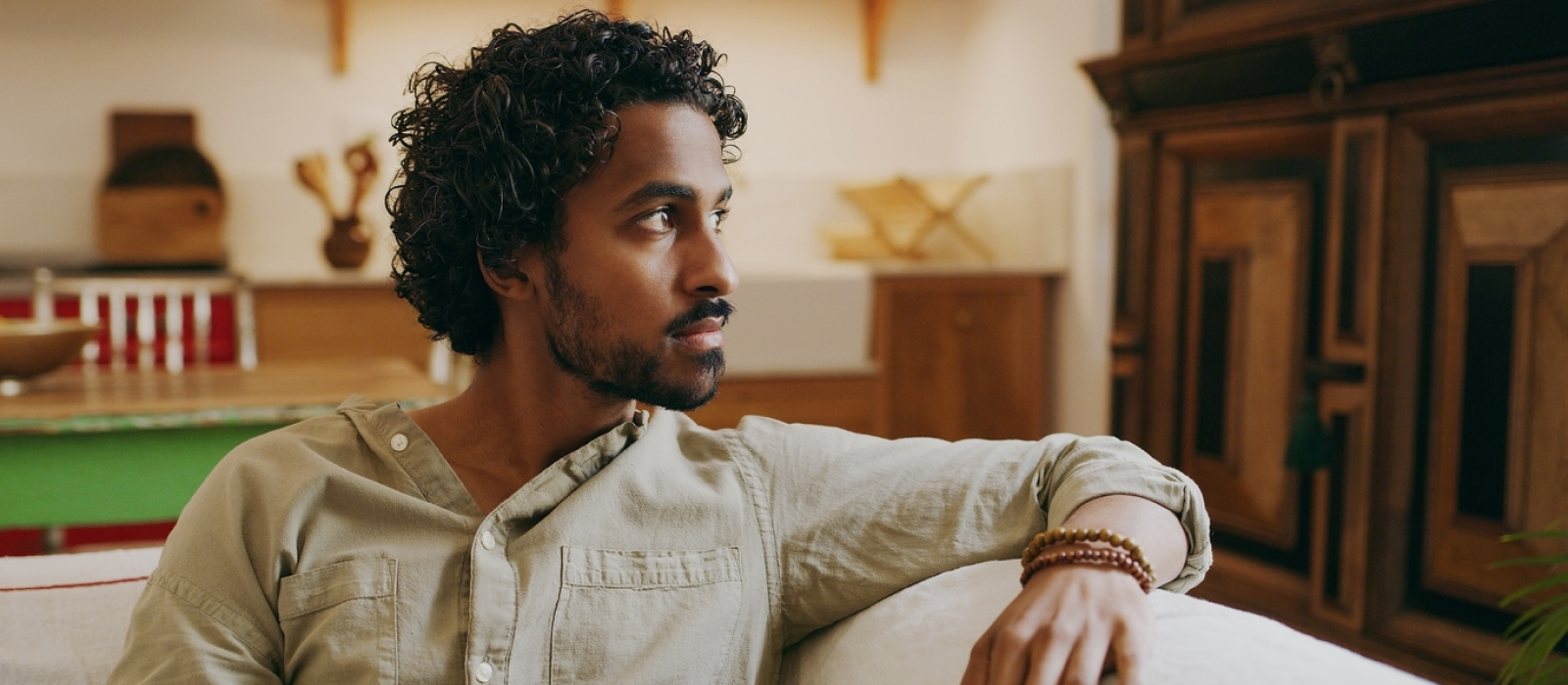 A young male sits on his couch. He is a survivor of intimate partner violence and is getting support at Charlie Health.