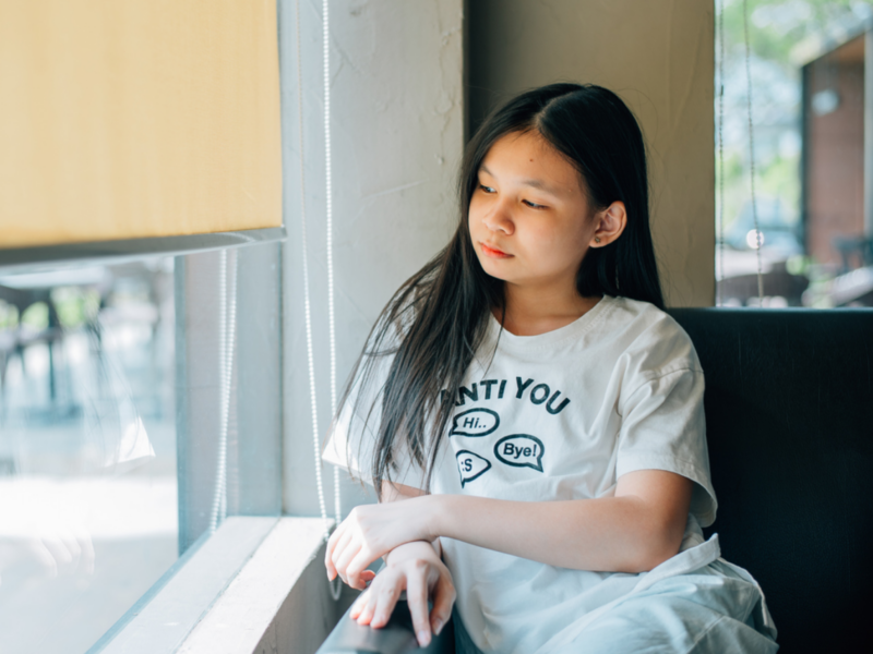 A female teenager sits in her house and looks out of her window. She has narcissistic personality disorder, which can be similar to borderline personality disorder.