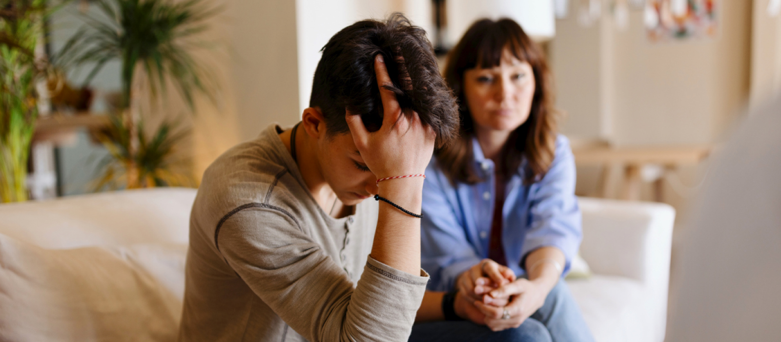 A young male sits with his mom at therapy. He is experiencing burnout as a young person new to the workforce.