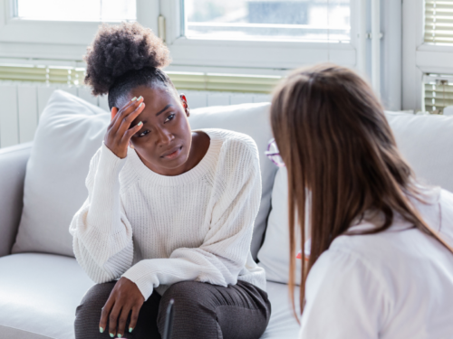 A young woman sits with a therapist. She has treatment-resistant OCD which may be why her OCD symptoms won't improve.