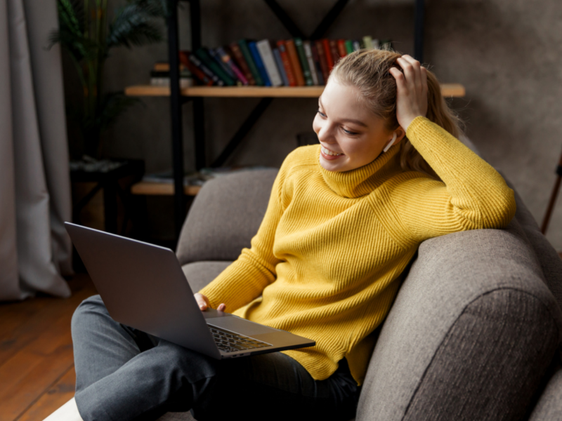 A young woman sits on her couch in virtual therapy. She is in therapy for PTSD from childhood trauma.