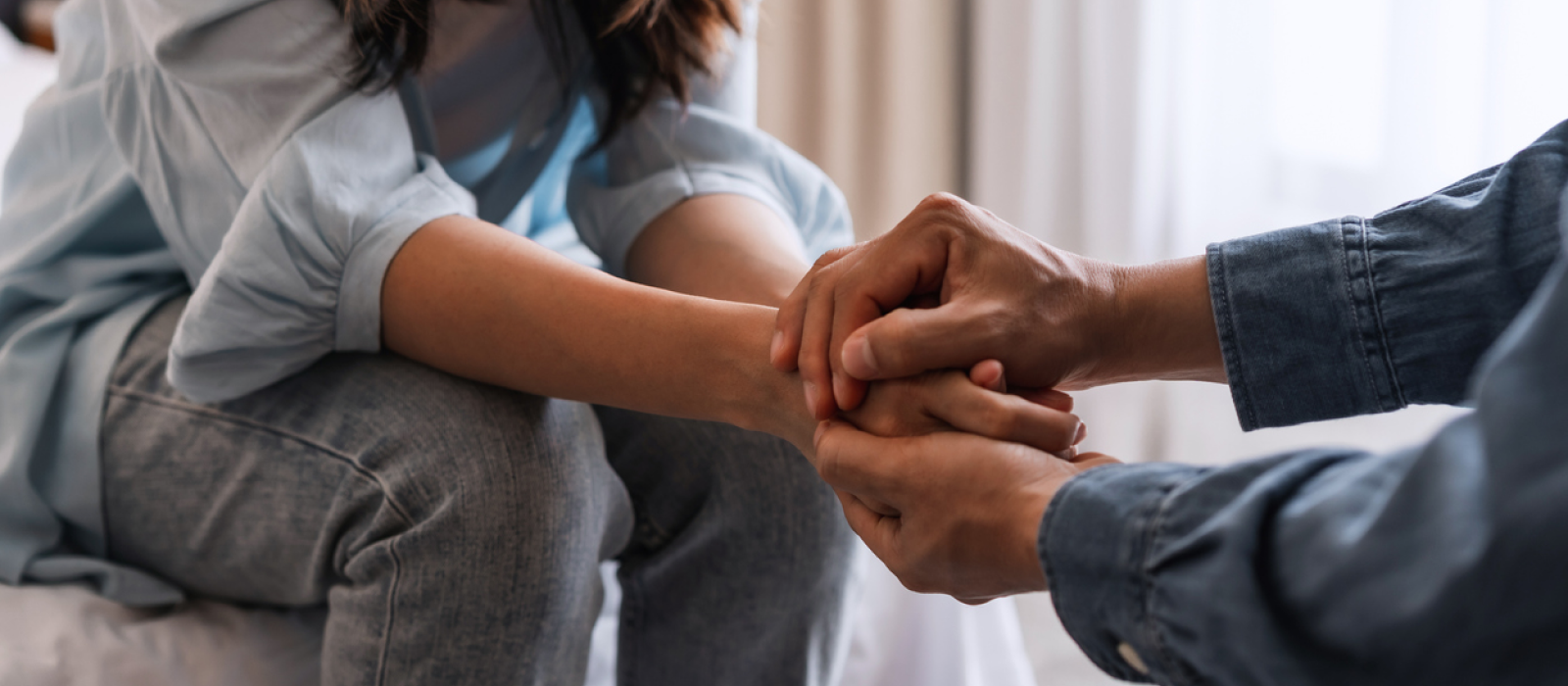 A young woman holds her partners hands to comfort him. He has experienced childhood emotional abuse and is having depressive symptoms as an adult.