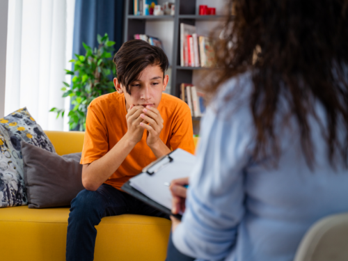A young teenager sits with a therapist. He is facing his fear of therapy.