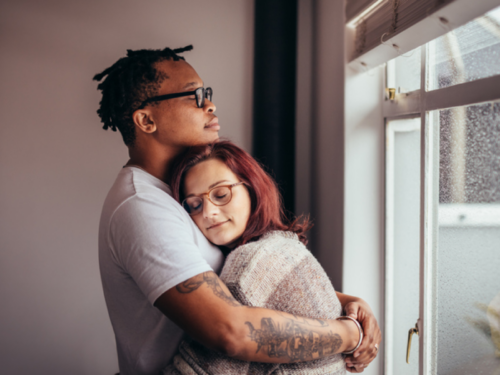 A young couple hugs in their home. They are a military family, prioritizing mental health.