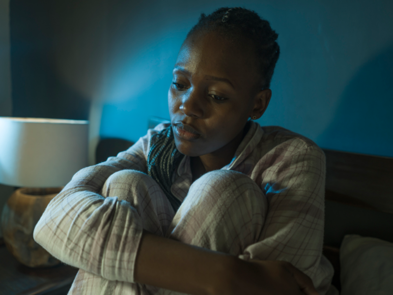 A young woman sits in bed. She has not been feeling like herself, and is figuring out if she has somatic symptom disorder or illness anxiety disorder.