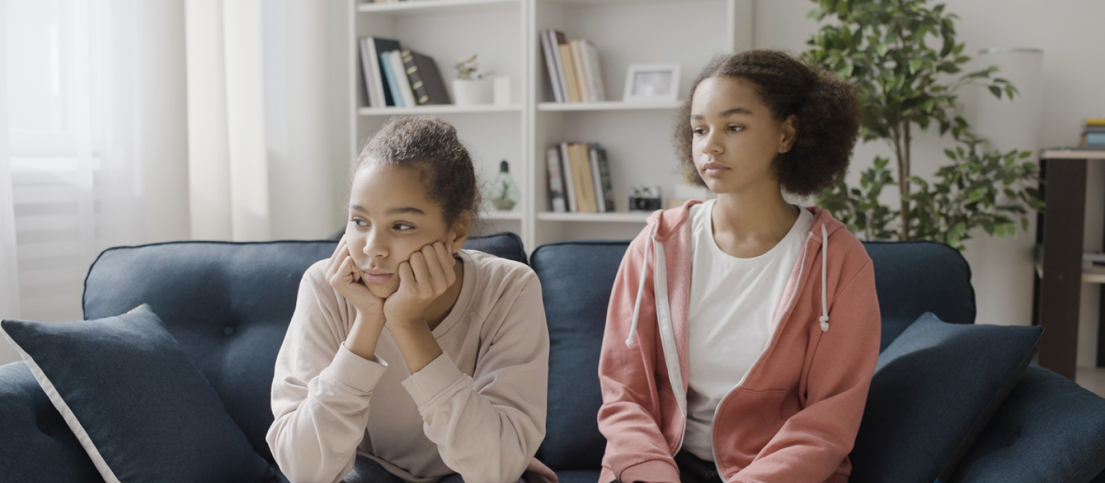 Two siblings sit on a couch. The middle child is having feelings of inadequacy.