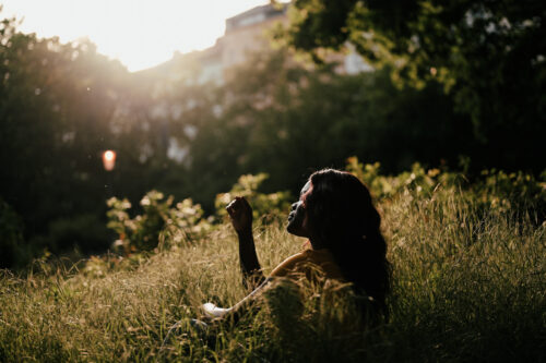 Woman sitting in field, practicing vagus nerve exercises