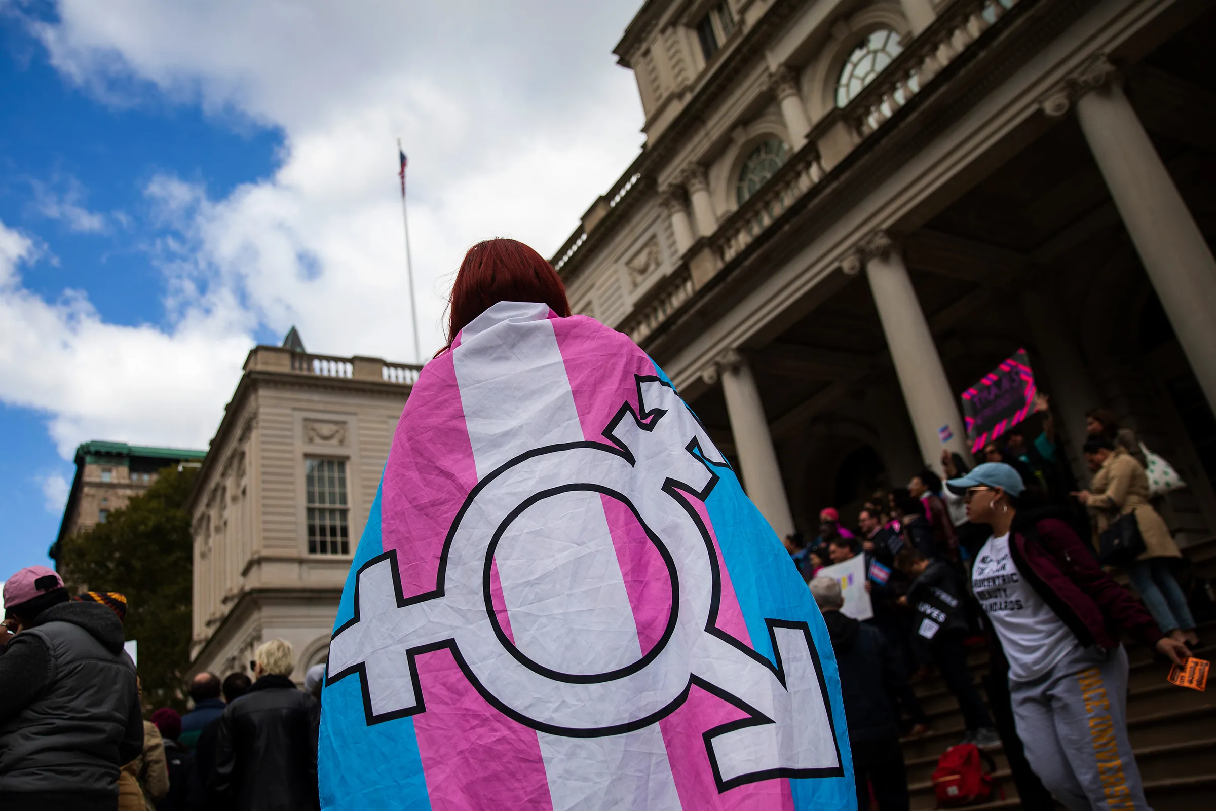 Person with the trans pride flag wrapped around them