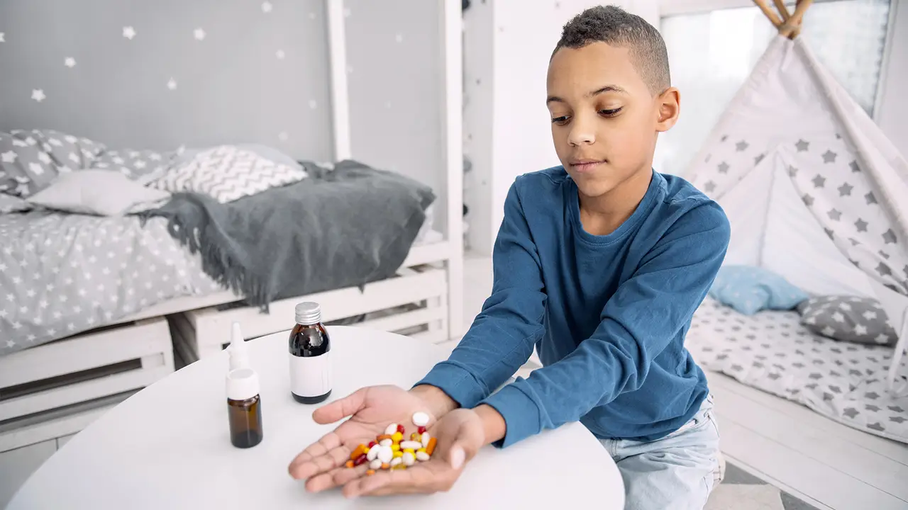 Young boy with all the medications he needs to take in his hands