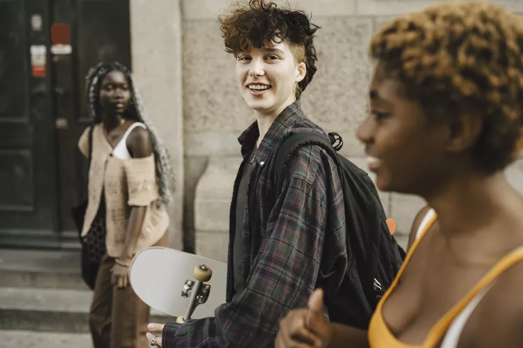 Nonbinary youth chatting as they walk down a street