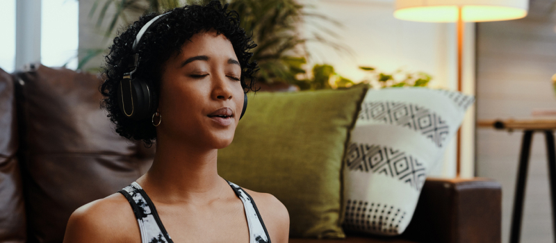 A person with headphones on practice relaxation techniques to calm anxiety-related shortness of breath.