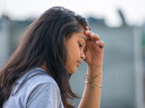 A young woman in a blue shirt thinks about how motivational interviewing could help her manage depression.