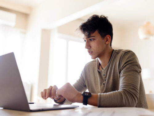 A boy in a henley sits at a computer searching for a group therapy for anger management session.