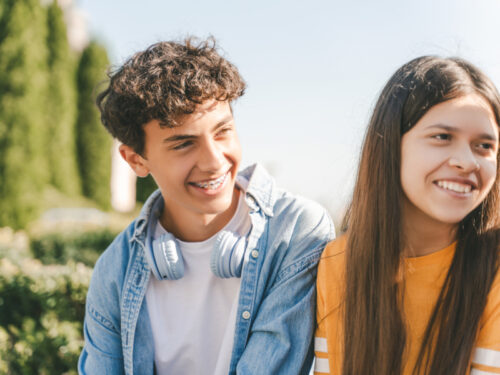 A boy with a white shirt and a girl with a yellow shirt smile after managing their anxiety in group therapy for anxiety.