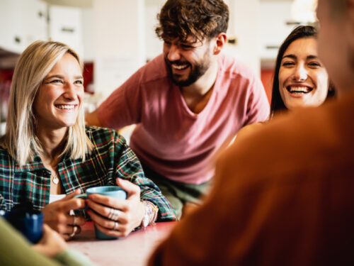 A group of three people in group therapy for depression sit together laughing.
