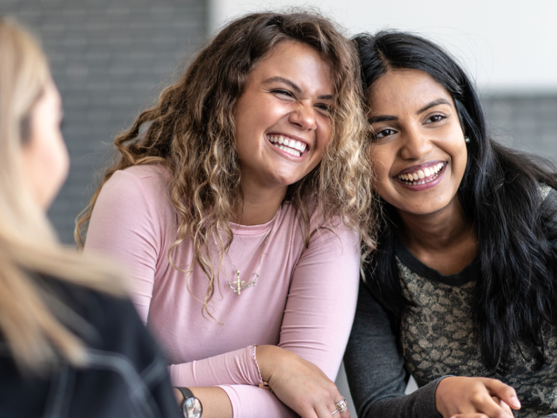 A pair of women sit next to each other in a group therapy for OCD session.