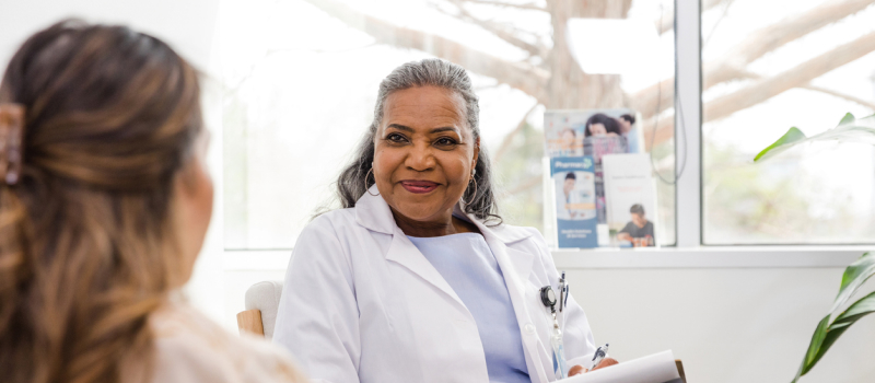 A female clinician wearing a white coat sits in a session with a client who she is considering prescribing an SSRI for bipolar for.