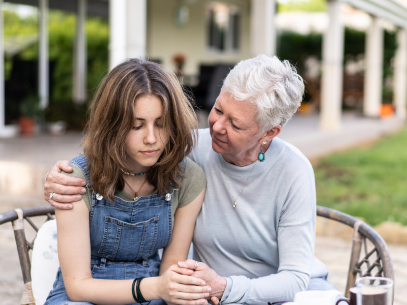 A young woman is in CBT for anxiety, her grandmother is giving her a hug.
