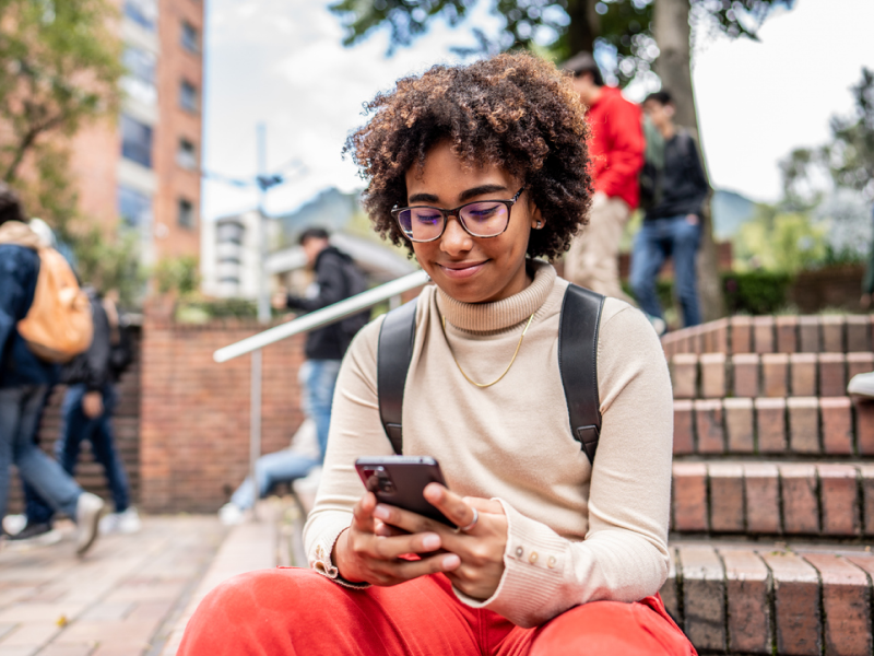 A young woman sits on steps researching everything she needs to know about CBT for bipolar disorder.