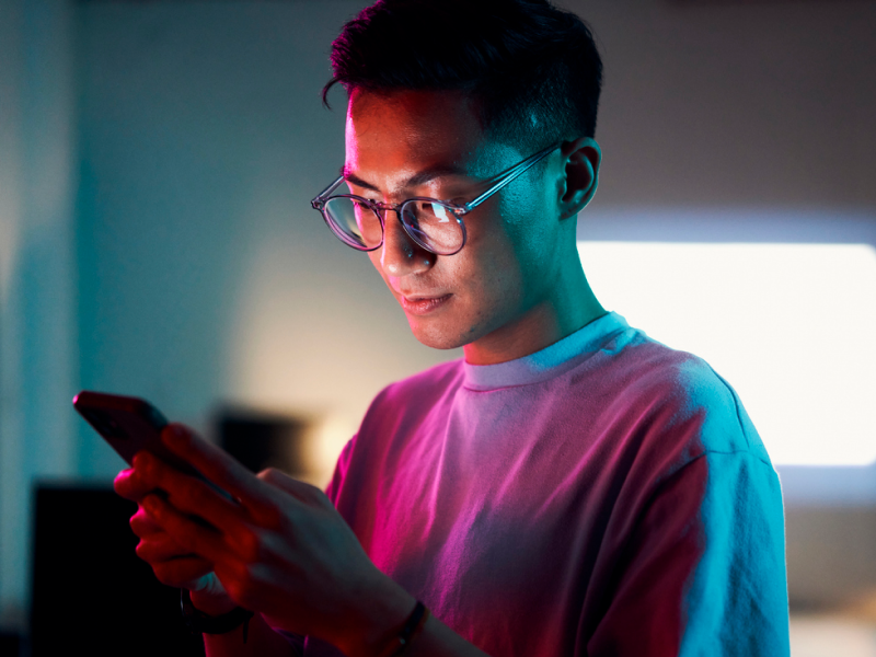 A young man looks up the key differences between youth and adult mental health on his phone.