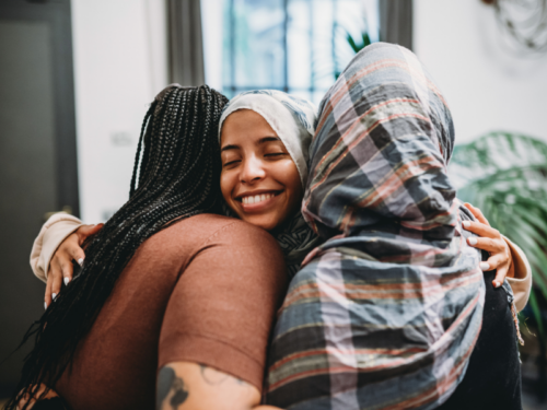 A young woman is in recovery from codependency, her friends are giving her a hug of support.