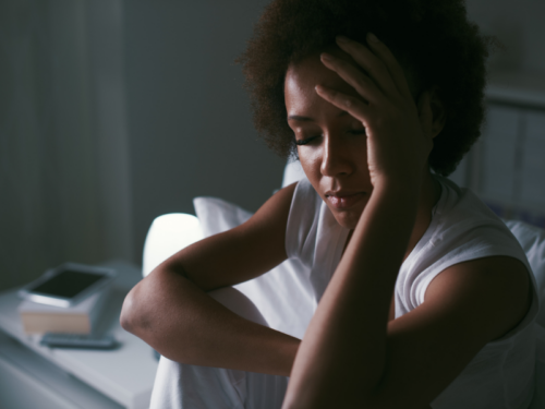 A woman is in bed at home feeling anticipatory anxiety.