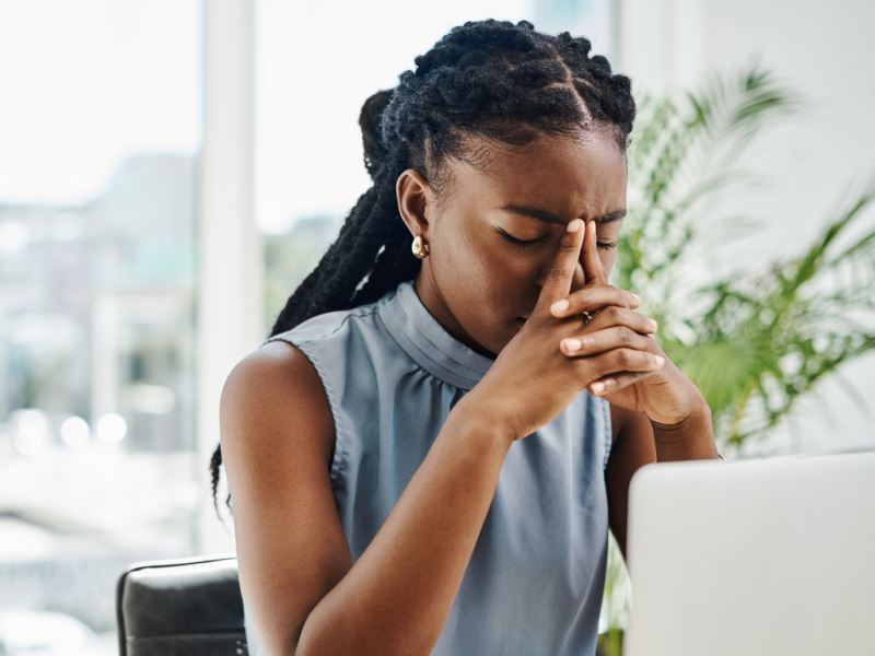 A young woman sits at work feeling work burnout.